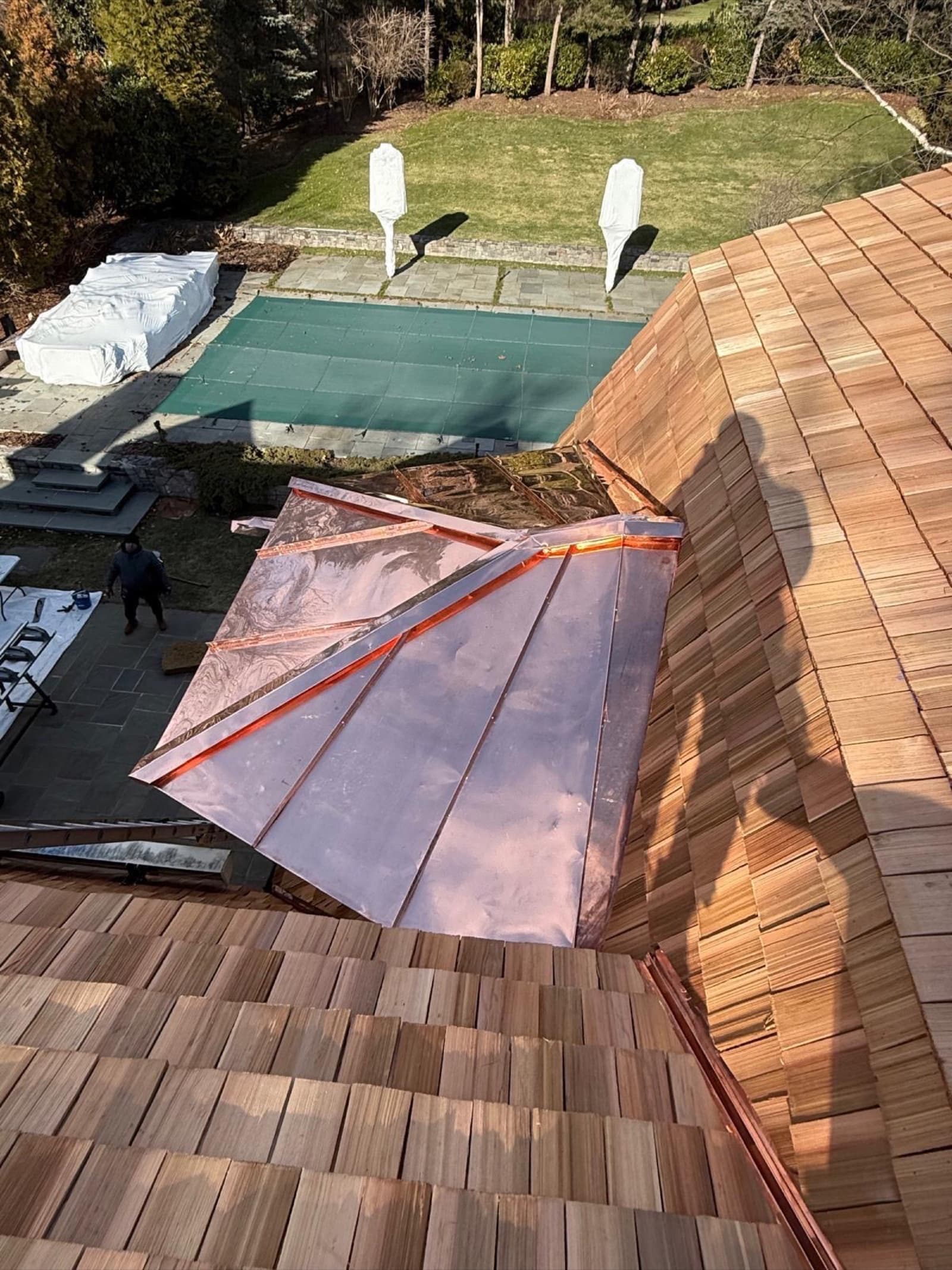 Copper standing-seam roof on a cedar-shake luxury home — premium metal accent installation by Zubar Roofing.