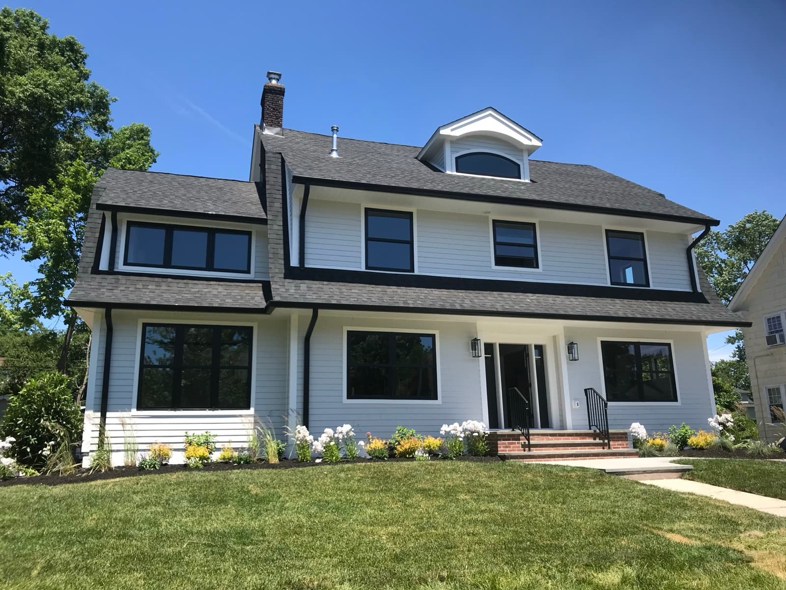 Newly completed black architectural shingle roof on a white colonial home in New Jersey by Zubar Roofing.